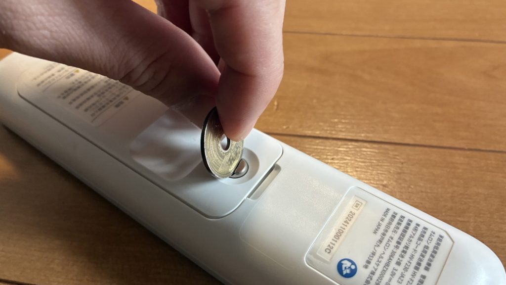 5円玉を使って電池蓋を開ける様子の実演画像