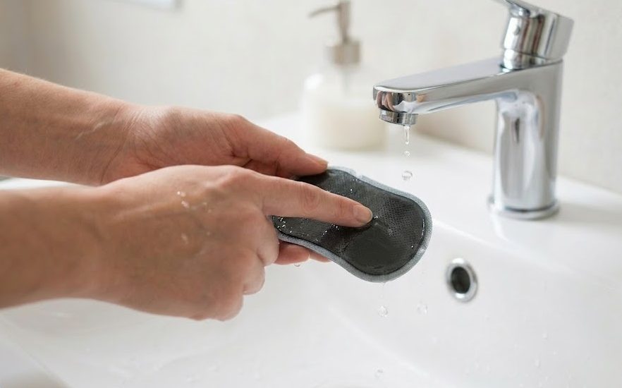 蛇口から滴る水滴で低周波治療器パッドの粘着面を優しく洗う様子