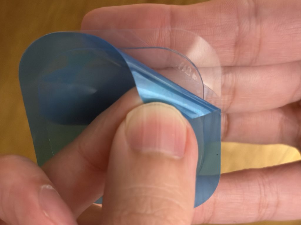 RYNEXT+の青い温熱替えパッドを手に持ち、保護フィルムをはがしかけた状態