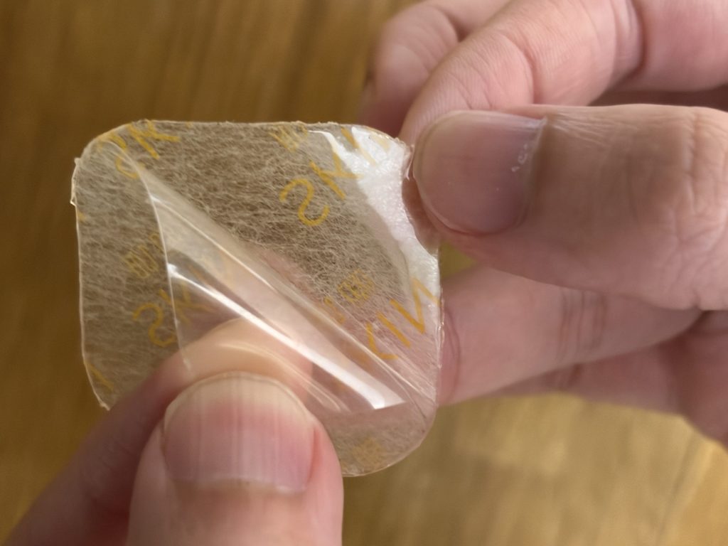粘着パッドから透明の保護フィルムをはがしているところ