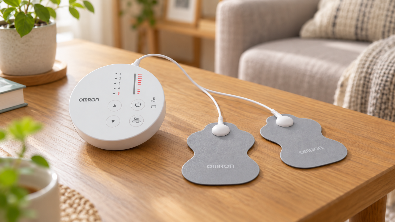リビングのテーブルに置いたオムロンの低周波治療器HV-F013の丸い本体と、コードでつないだグレーのロングライフパッド2枚